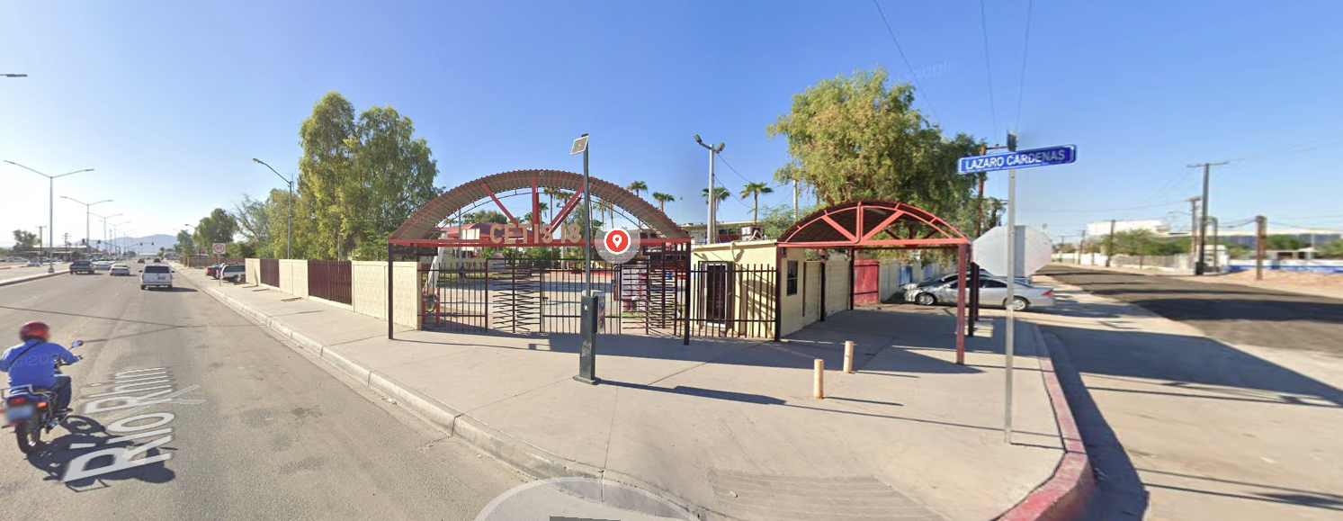 En la esquina de la calle Lázaro Cárdenas se encuentra la entrada del plantel y el acceso está conformado por una reja color rojo con torniquetes, sobre ella en letras grandes dice CETIS 18.